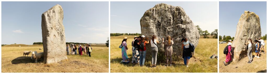 Women touching the ancient stones with sheep at Avebury stone circle during a spiritual retreat in Somerset