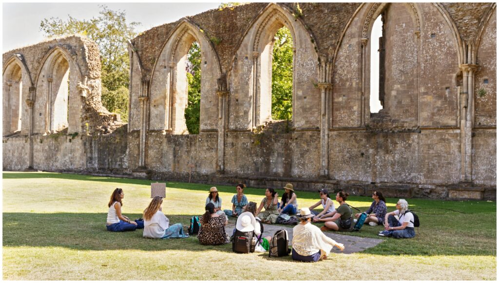 Women gathered in meditation around the tomb of King Arthur at Glastonbury Abbey in Somerset