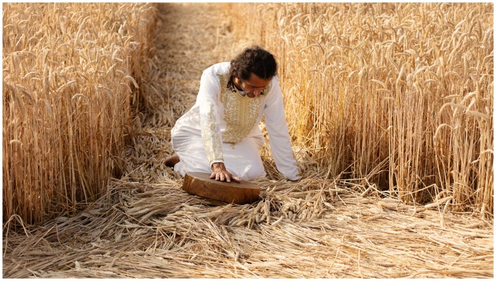 Shaman kneeling with a drum inside a crop circle formation in Somerset