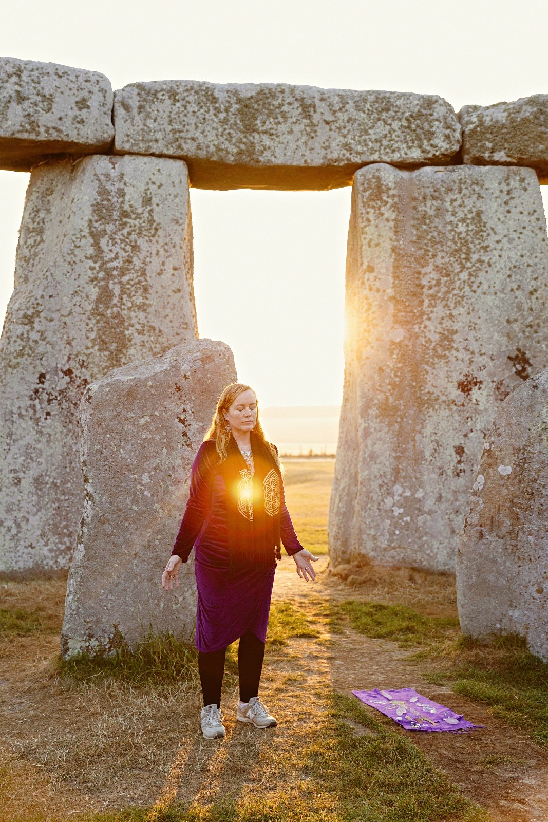 Katy Sophia standing in the Stonehenge circle at sunrise during an Avalon spiritual retreat
